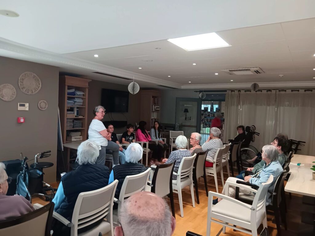 Groupe d’aînés assis en cercle lors d’une discussion ou animation dans une salle lumineuse.
