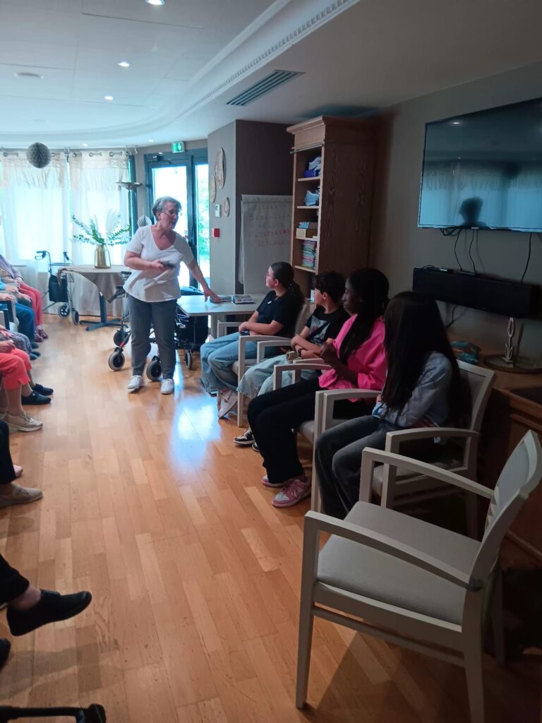 Atelier en intérieur : une femme présente quelque chose à un groupe assis en cercle, dont des personnes en fauteuil roulan