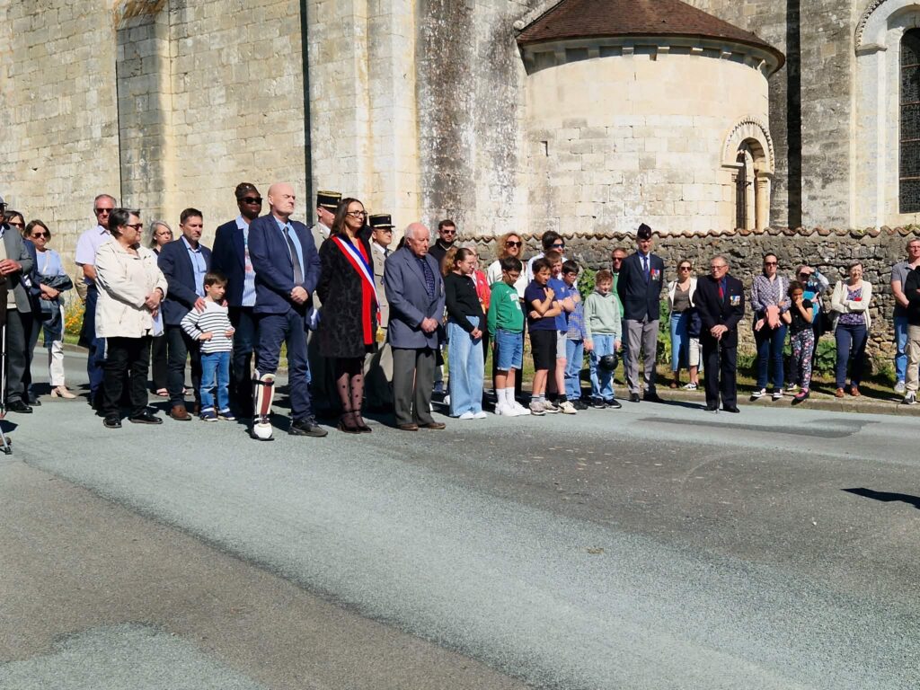 Groupe de personnes en tenue formelle et civile devant un édifice ancien, participant à une cérémonie commémorative.