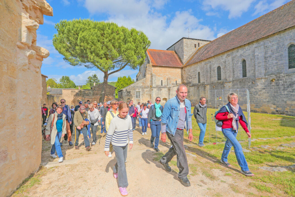 Groupe de visiteurs se promenant dans une ancienne abbaye en ruines sous un ciel dégagé.