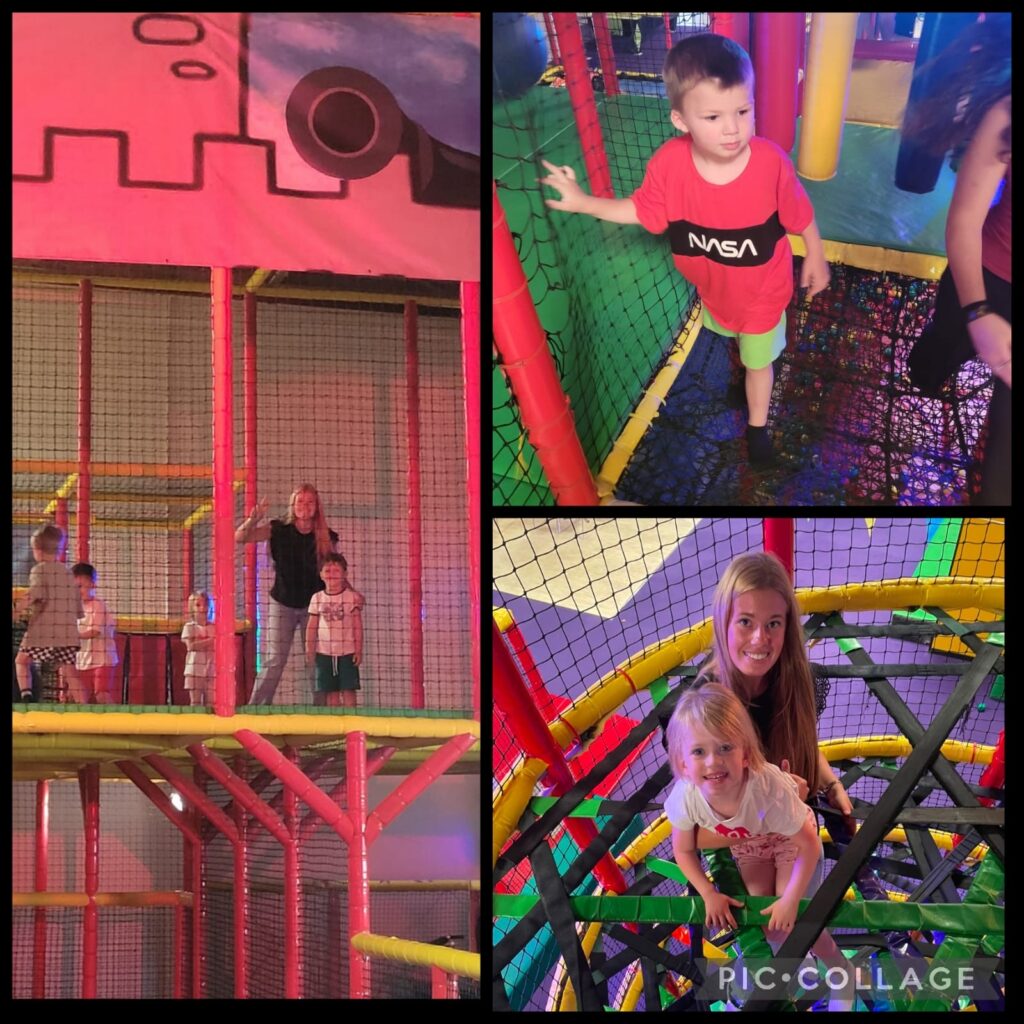 Enfants jouant dans un parc aventure intérieur coloré avec structures en filets et tubes.