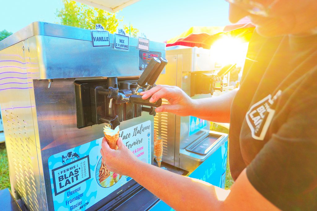 Ice à la vanille et mangue servi dans un cornet, machine à glace artisanale ensoleillée.