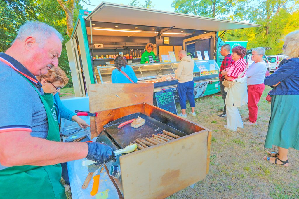 Groupe de personnes devant un food truck grillant des saucisses en plein air, marché convivial.
