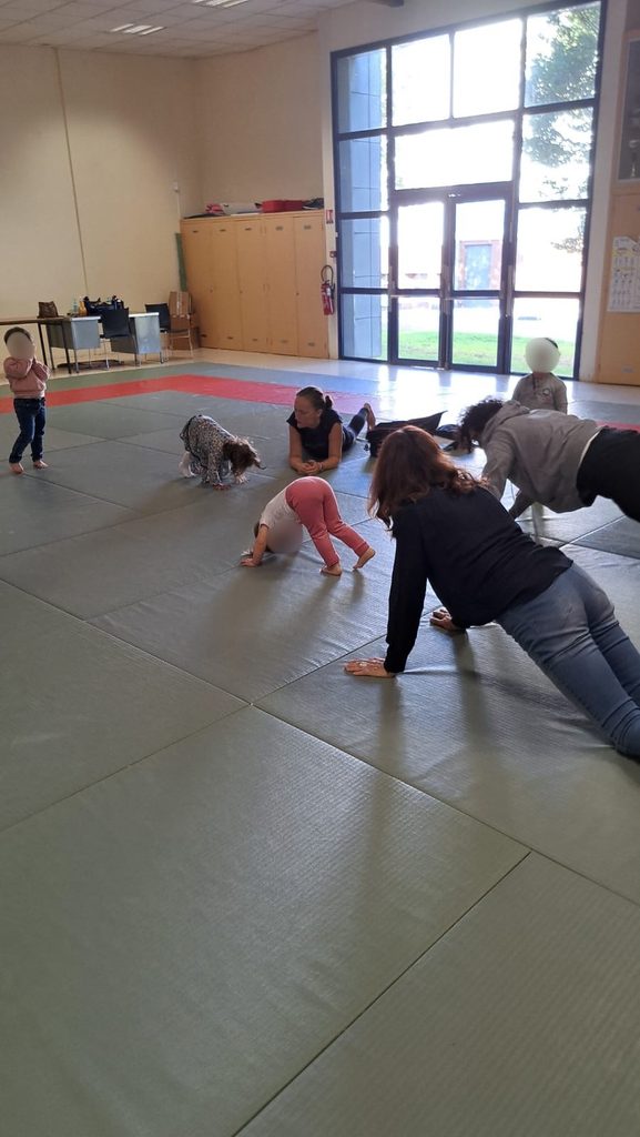 Enfants et adultes s’amusent avec des chiens dans une salle couverte, activité ludique et interactive.