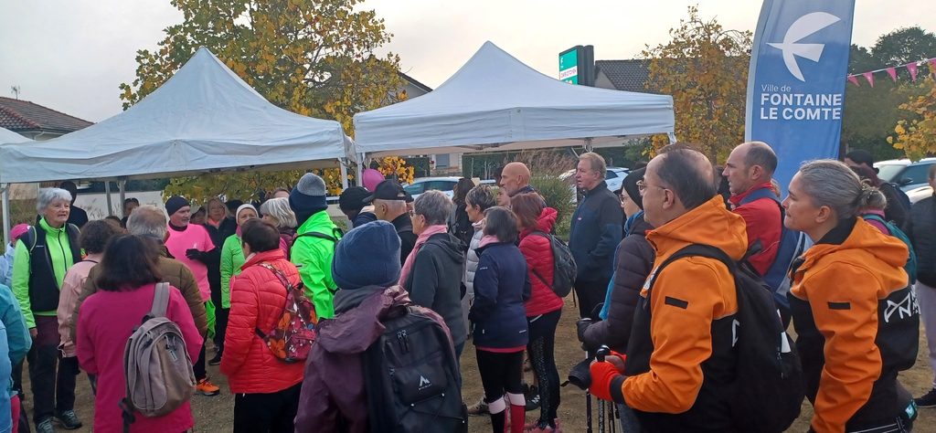 Groupe de participants à un événement sportif à Fontaine-le-Comte, sous tente, en discussion, vêtus de vêtements chauds