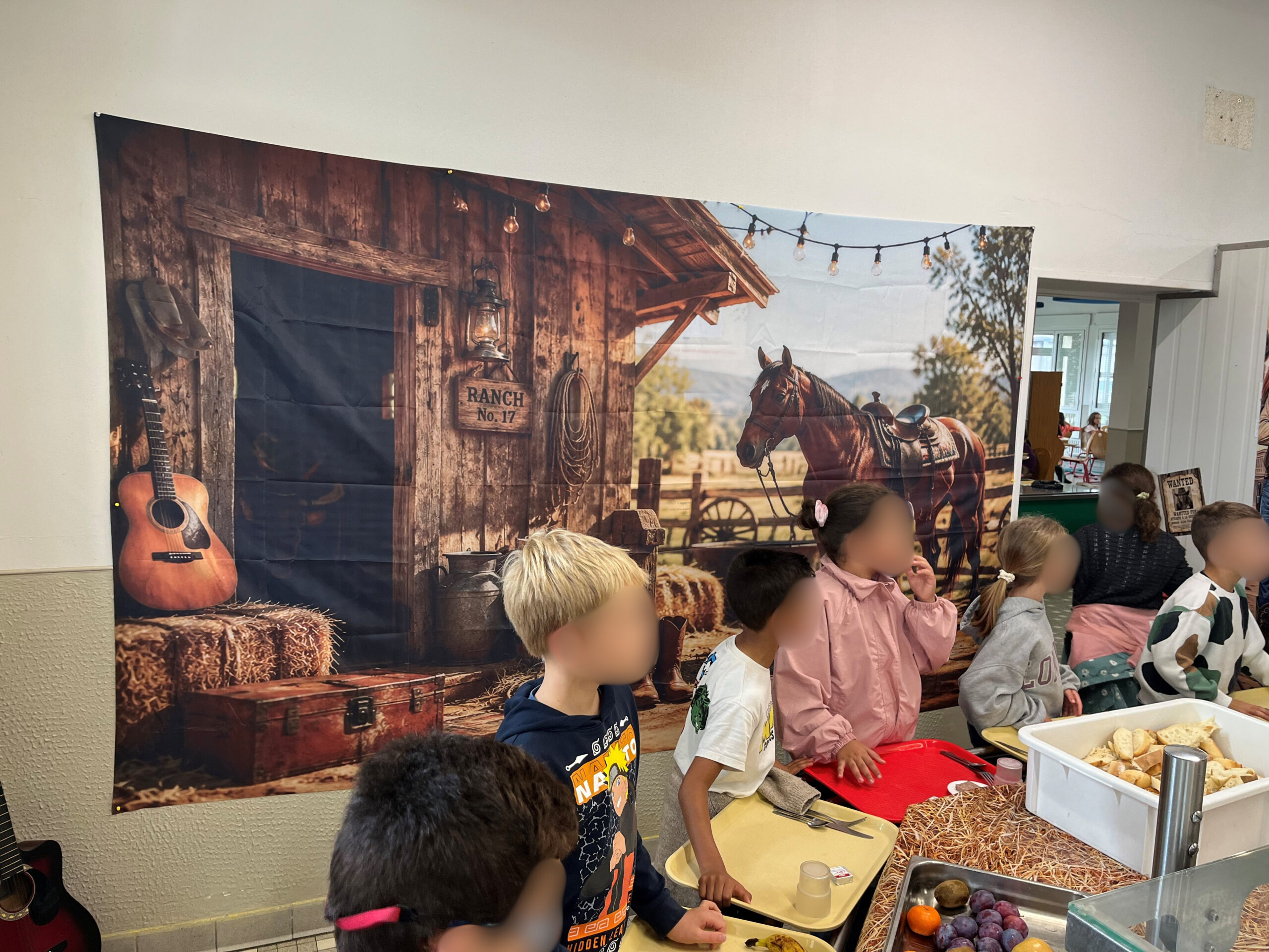 Enfants assis devant une décoration murale western, mangeant lors d’un repas thématique ranch.