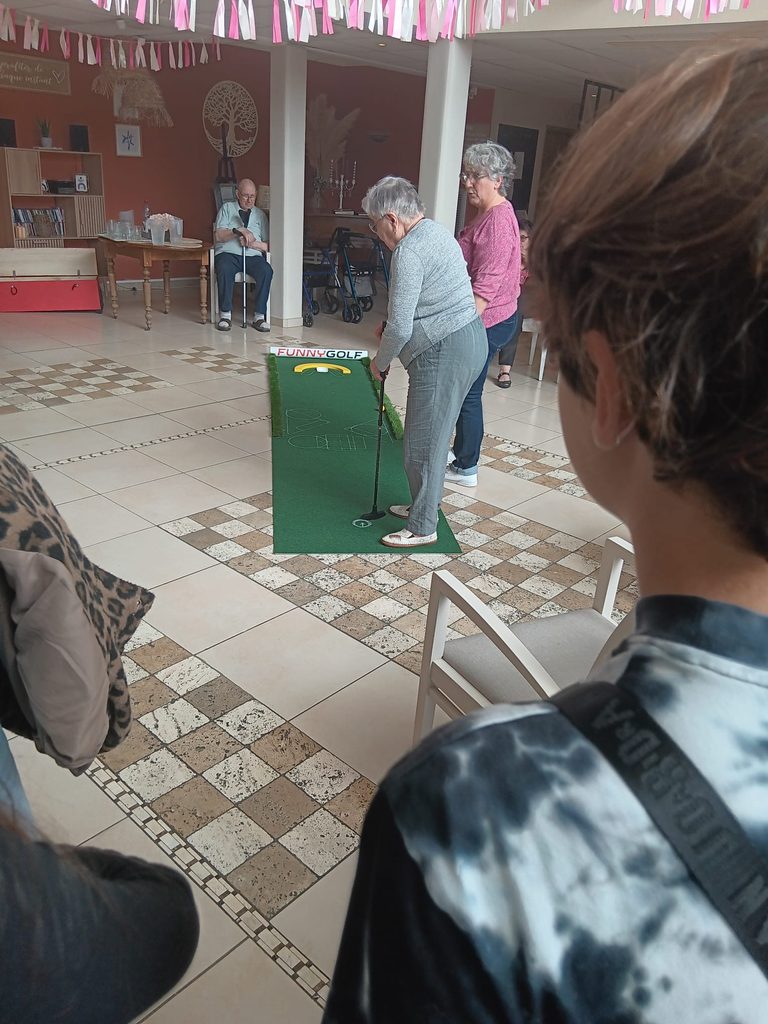 Personnes jouant au mini-golf en intérieur, spectacle convivial avec participants et spectateurs.
