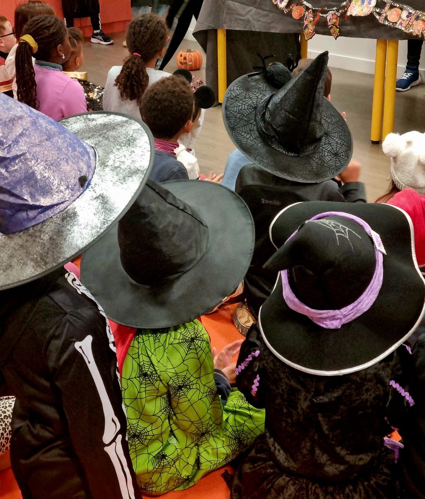 Enfants déguisés en sorcières avec chapeaux pointus, participant à un événement festif.